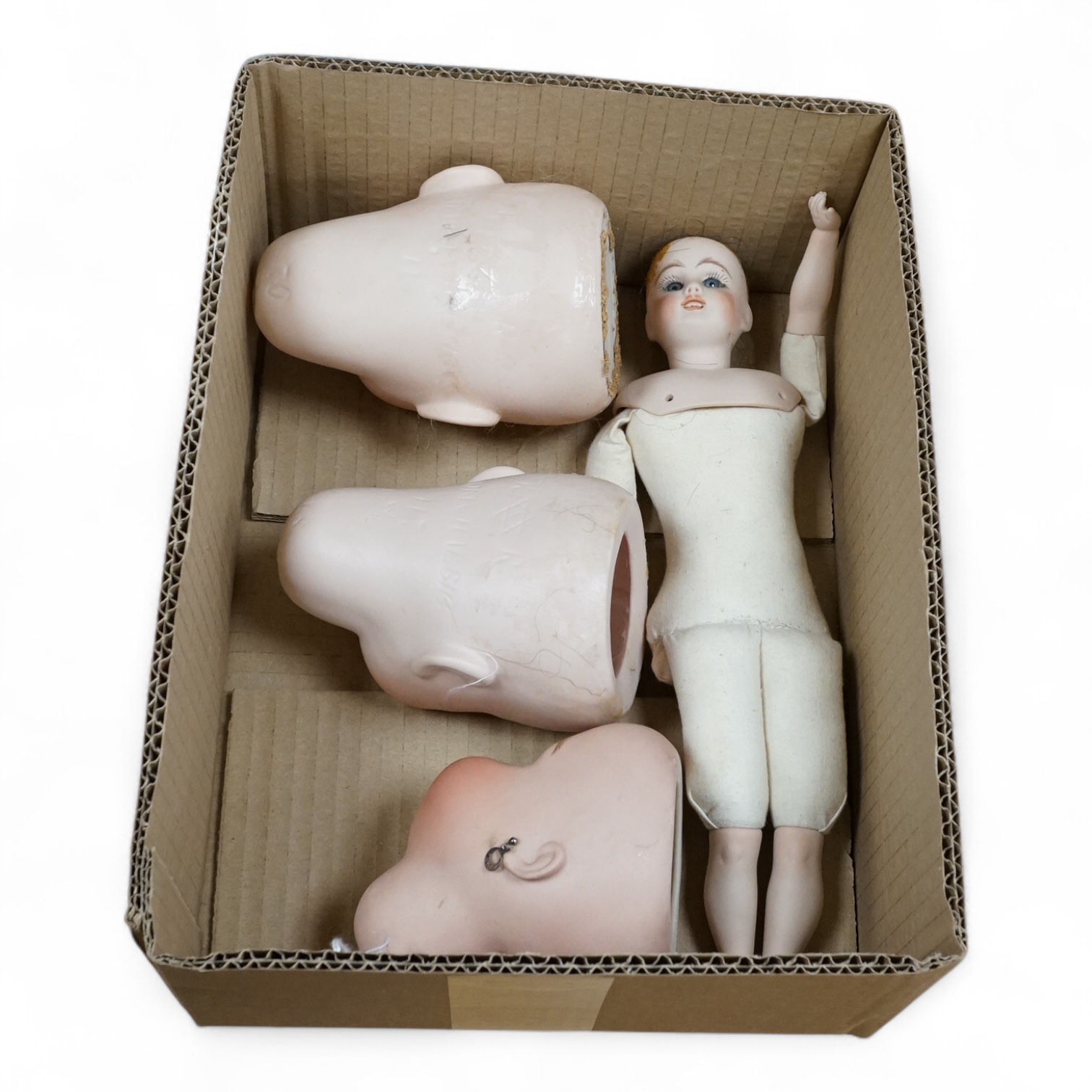 A small doll (30cm high) with bisque head and limbs, and fabric body, together with three doll’s heads; two by Simon and Halbig - models 68 and 70, and a modern head by Hathersage AMW 1994. Condition - fair.